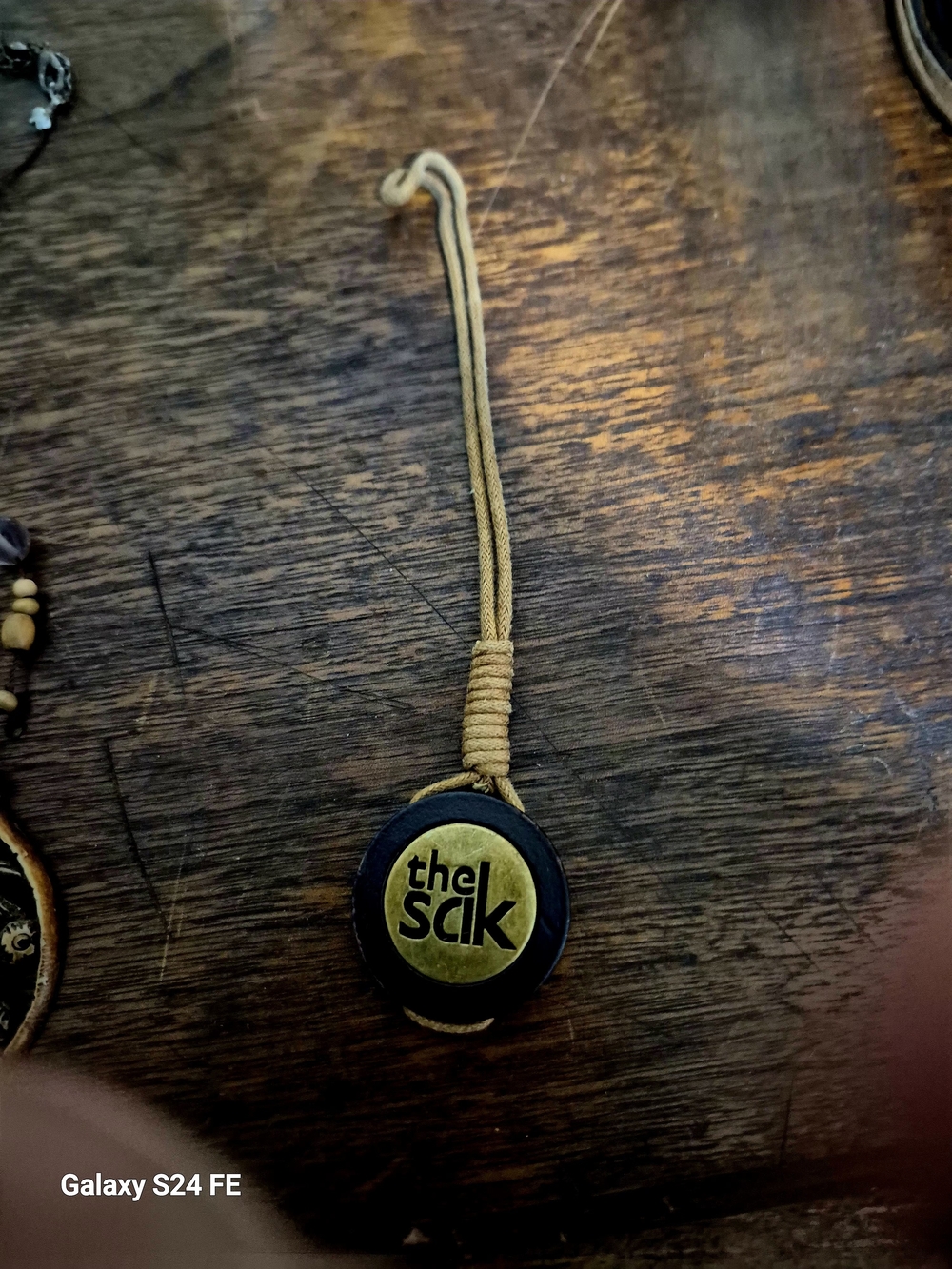The Sak Black and Tan Logo Cord Charm